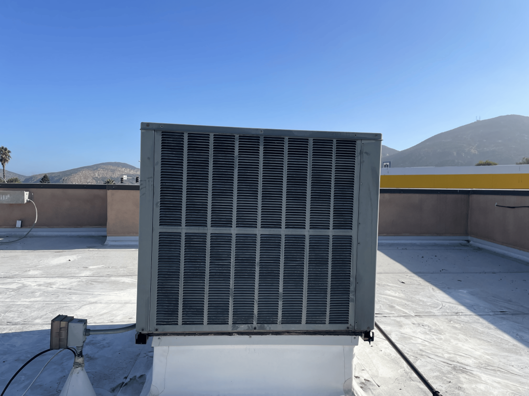 A heat pump installed on a rooftop under a clear blue sky, showcasing modern energy-efficient technology.