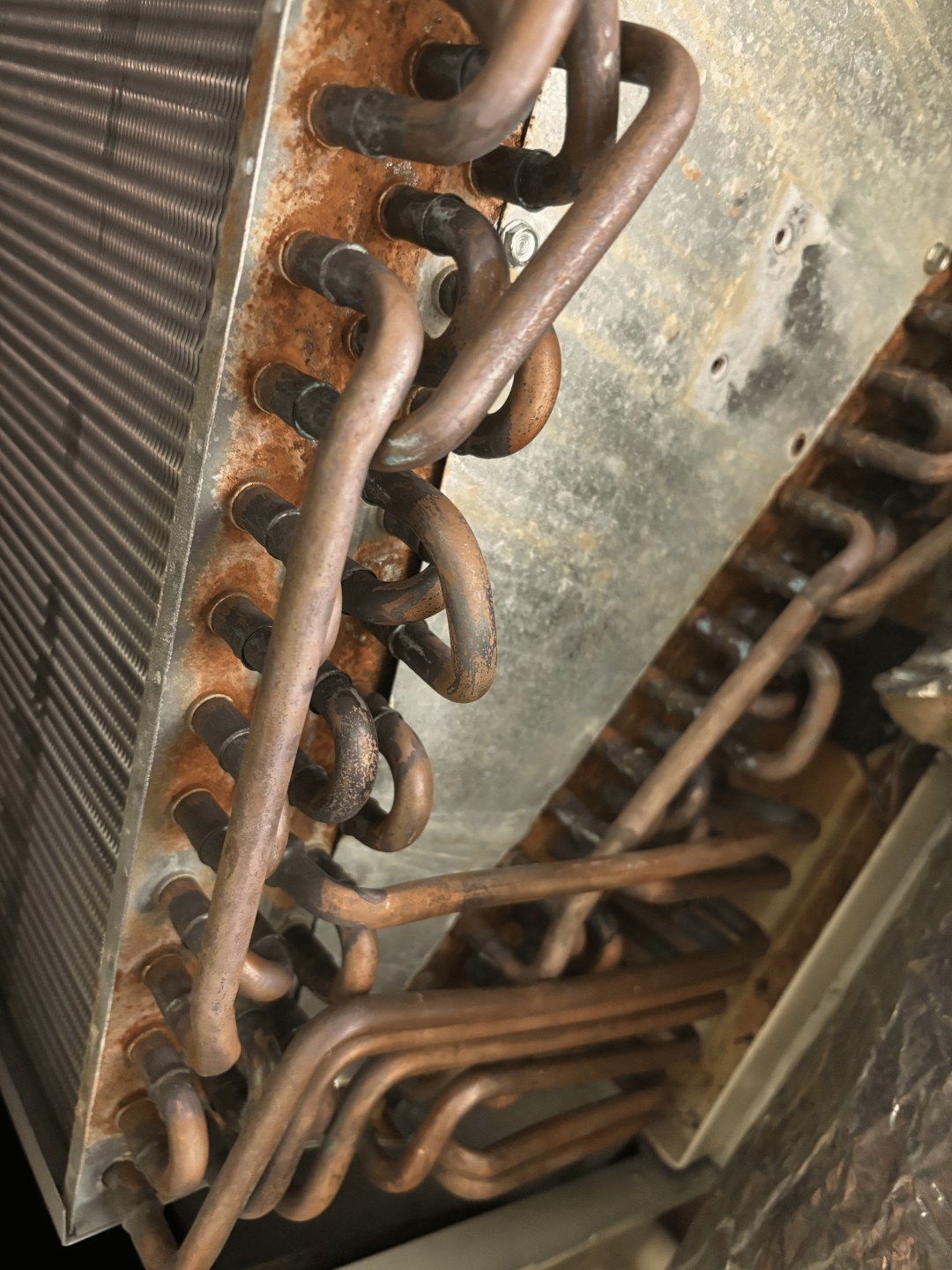 A close-up view of a metal pipe surrounded by several rusty pipes, showcasing their weathered textures and colors.