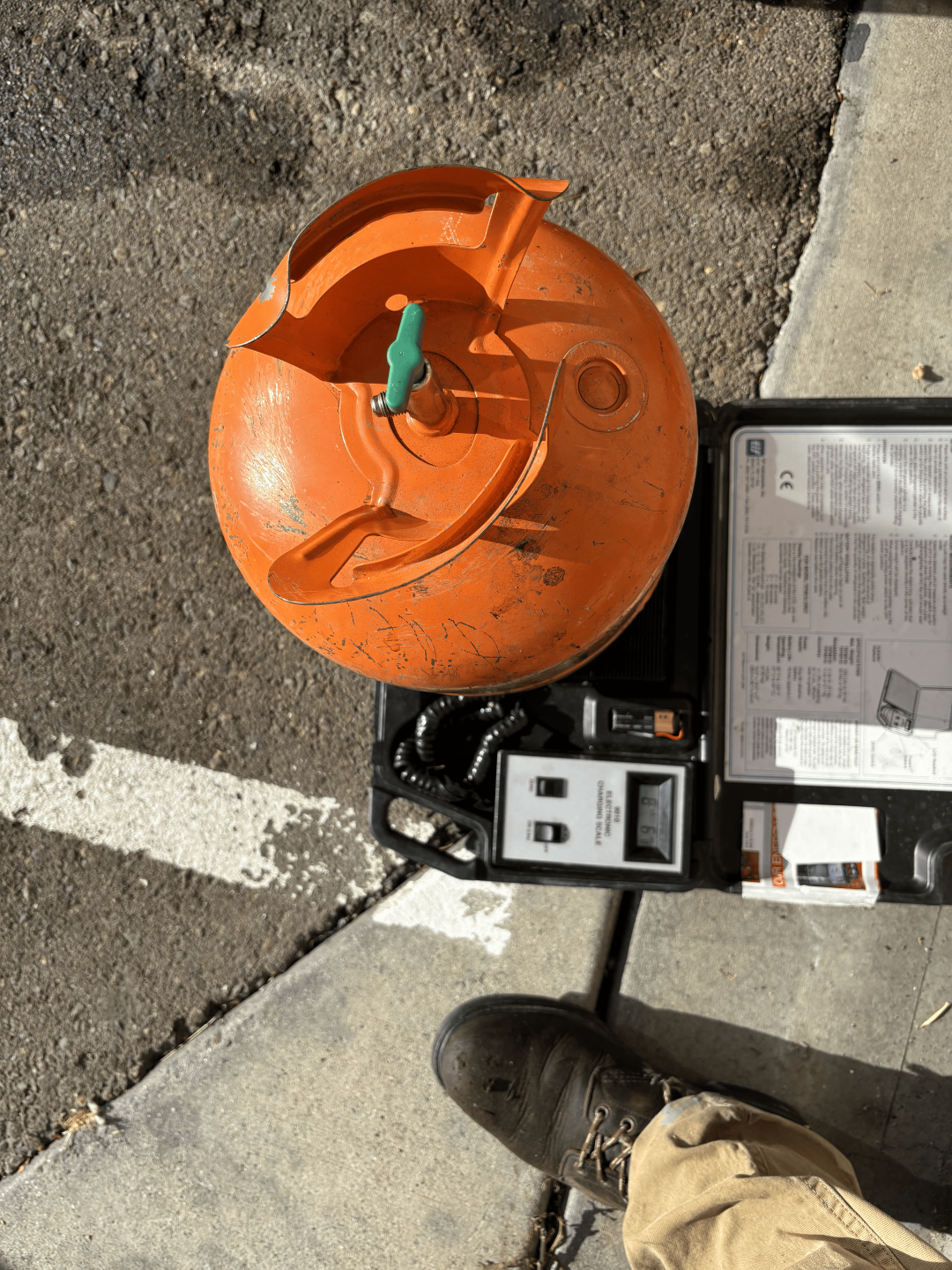 A man positioned at the street corner with a tank and equipment.